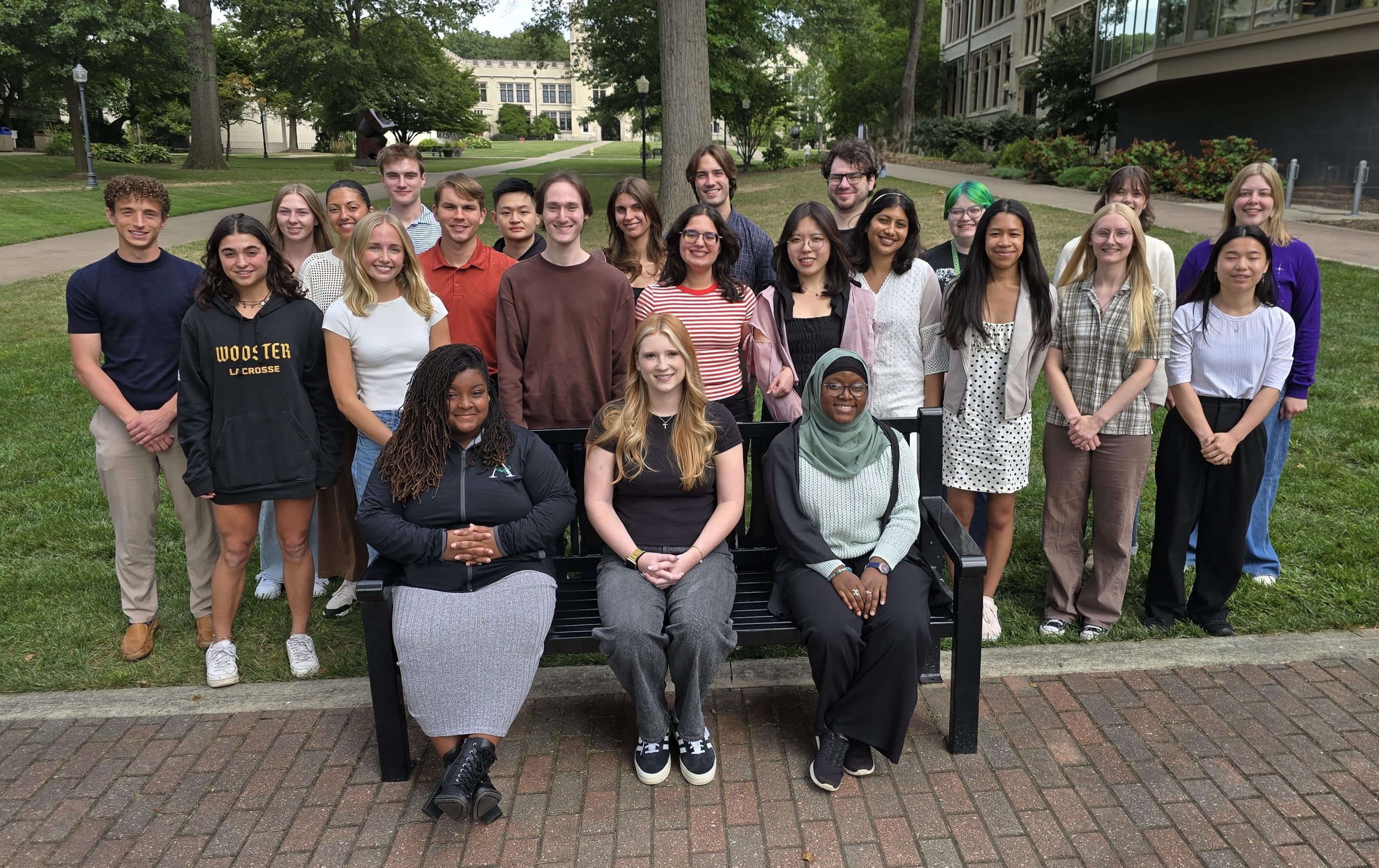 photo of college students sitting and standing around abench